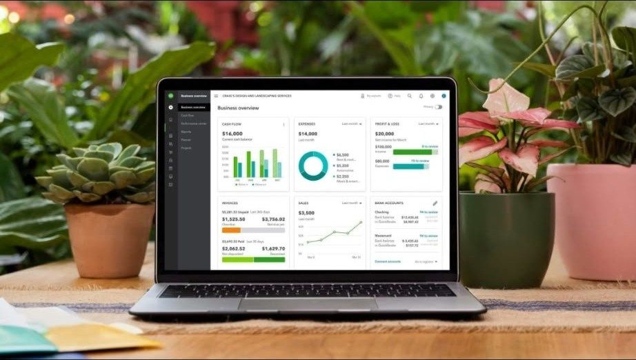Laptop showing a QuickBooks-style business dashboard among plants